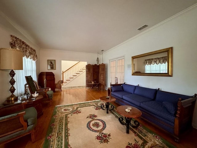 living room with visible vents, wood finished floors, ornamental molding, and stairs