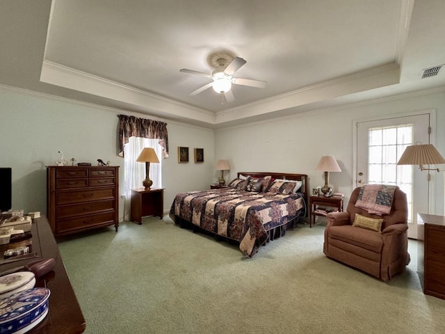 carpeted bedroom with ornamental molding, visible vents, ceiling fan, and a tray ceiling