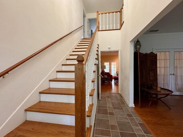 stairway featuring baseboards, visible vents, and a high ceiling
