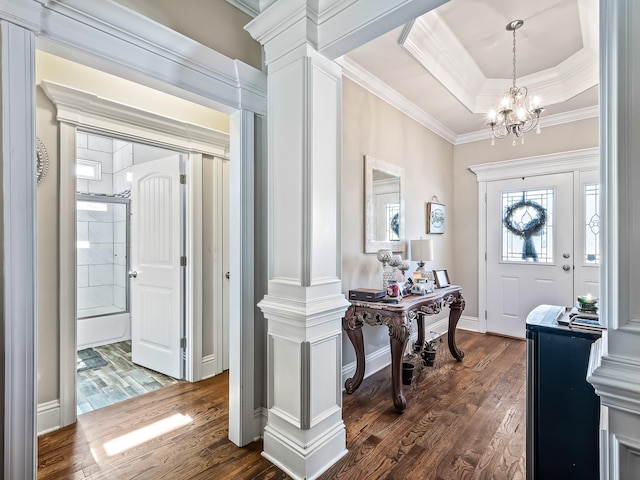 entryway featuring a tray ceiling, ornate columns, dark hardwood / wood-style flooring, and ornamental molding