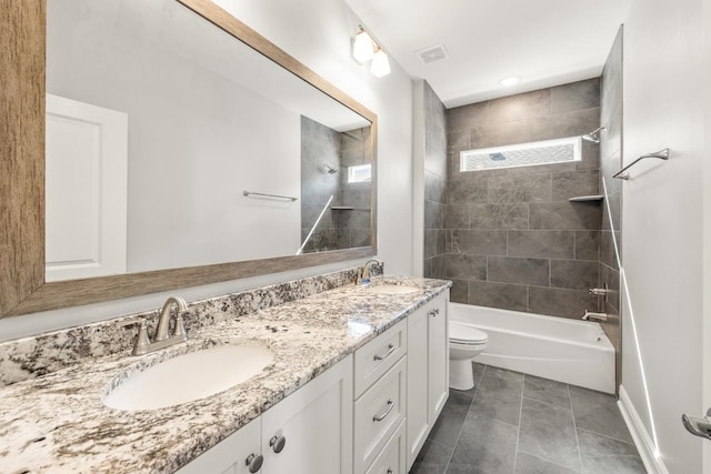 full bathroom featuring tile patterned flooring, vanity, tiled shower / bath combo, and toilet