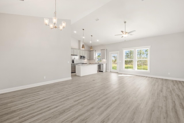 unfurnished living room featuring light hardwood / wood-style flooring, high vaulted ceiling, and ceiling fan with notable chandelier