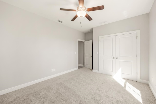 unfurnished bedroom featuring light carpet, a closet, and ceiling fan