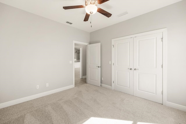 unfurnished bedroom with ceiling fan, light carpet, and a closet