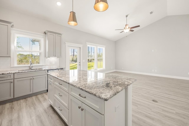 kitchen featuring gray cabinetry, a center island, sink, vaulted ceiling, and decorative backsplash