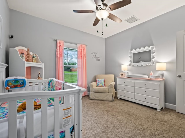 bedroom featuring ceiling fan, a crib, and light carpet