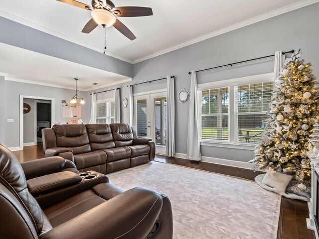 living room featuring crown molding, dark wood-type flooring, and ceiling fan with notable chandelier