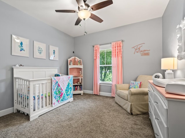 carpeted bedroom featuring ceiling fan and a nursery area