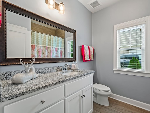 bathroom featuring plenty of natural light, vanity, hardwood / wood-style floors, and toilet