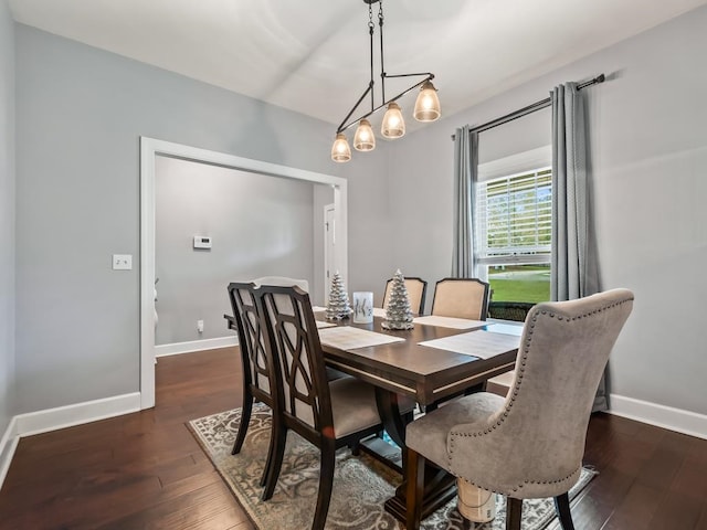 dining space featuring dark wood-type flooring and a notable chandelier