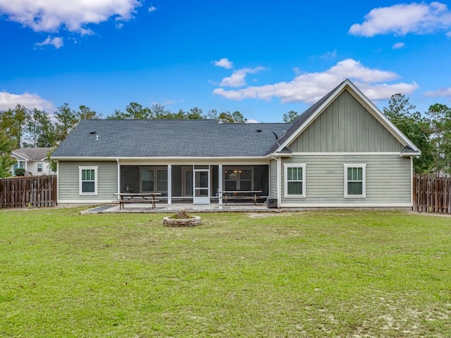 rear view of property featuring a yard, an outdoor fire pit, a patio area, and a sunroom