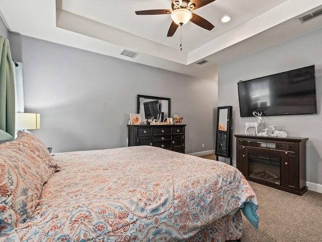 carpeted bedroom with a tray ceiling and ceiling fan