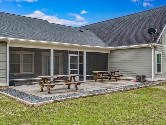 rear view of property featuring a lawn, a sunroom, and a patio area