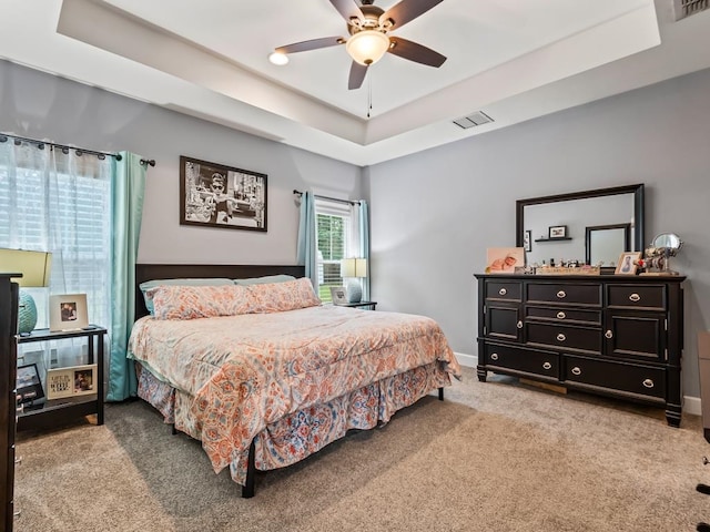 carpeted bedroom featuring ceiling fan and a raised ceiling