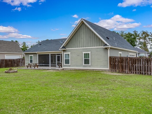 rear view of property with a fire pit, a sunroom, a yard, and a patio