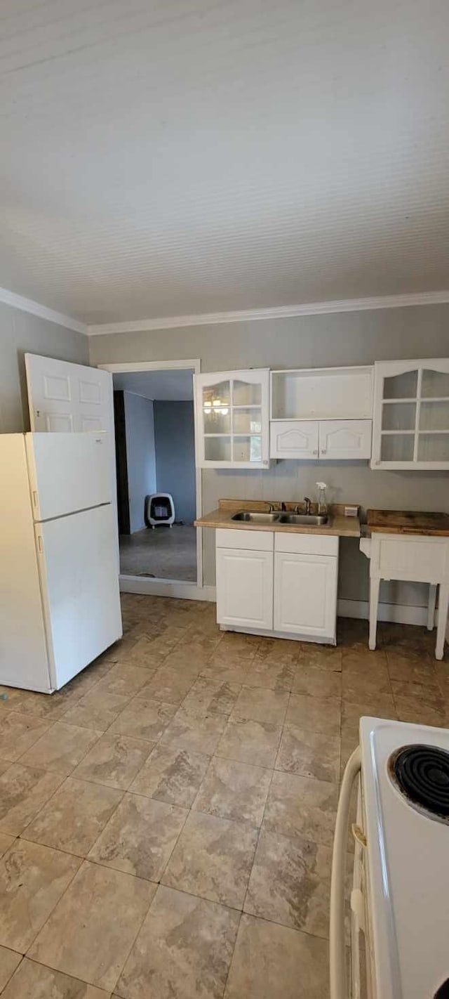 kitchen with white appliances, white cabinets, ornamental molding, light countertops, and a sink