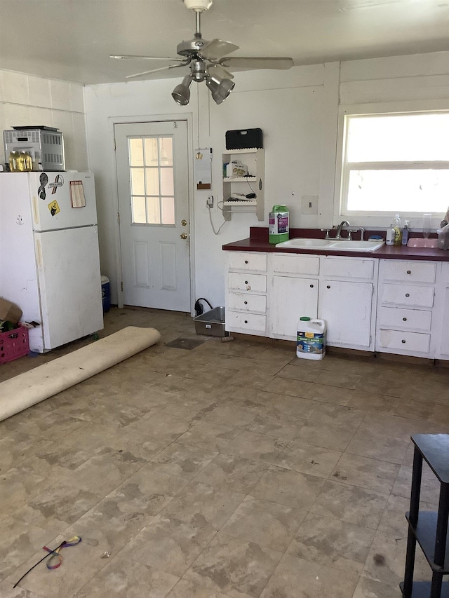 kitchen featuring a wealth of natural light, dark countertops, and freestanding refrigerator