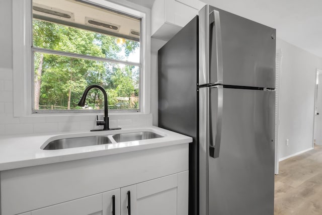 319 Meadowbrook Ln, Tallahassee, FL 32304 - kitchen featuring freestanding refrigerator, a sink, light countertops, white cabinets, and light wood finished floors