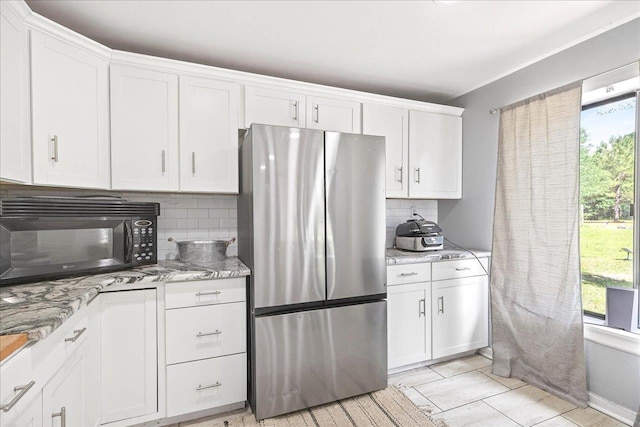 147 Hawk Ridge Dr, Havana, FL 32333 - kitchen featuring freestanding refrigerator, black microwave, decorative backsplash, white cabinets, and light stone counters