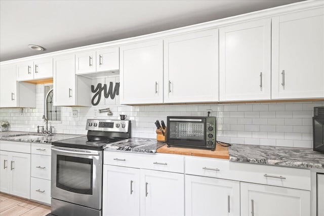 147 Hawk Ridge Dr, Havana, FL 32333 - kitchen with stainless steel electric stove, backsplash, white cabinetry, and light stone countertops