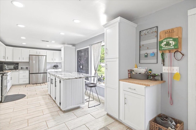 147 Hawk Ridge Dr, Havana, FL 32333 - kitchen featuring freestanding refrigerator, tasteful backsplash, black microwave, white cabinets, and recessed lighting