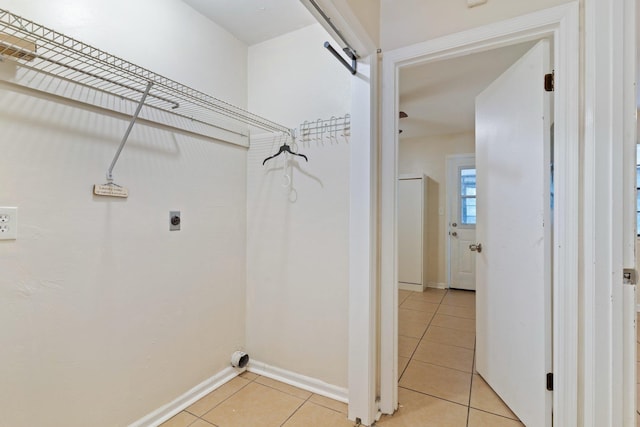 clothes washing area featuring a barn door, electric dryer hookup, and light tile patterned floors