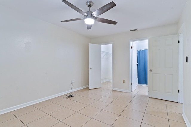 unfurnished bedroom featuring ceiling fan, a walk in closet, a closet, and light tile patterned flooring