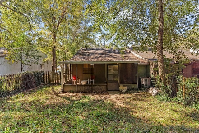 rear view of house with cooling unit, a sunroom, and a lawn