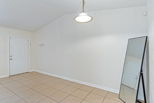 tiled empty room featuring vaulted ceiling