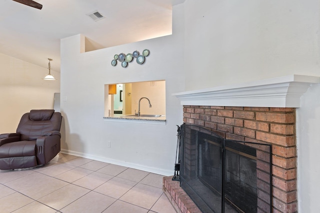 living room with sink, a brick fireplace, tile patterned floors, and vaulted ceiling