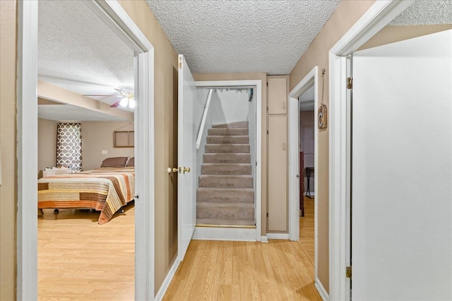 corridor featuring a textured ceiling and light wood-type flooring