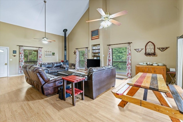 living room with high vaulted ceiling, plenty of natural light, and light wood-type flooring