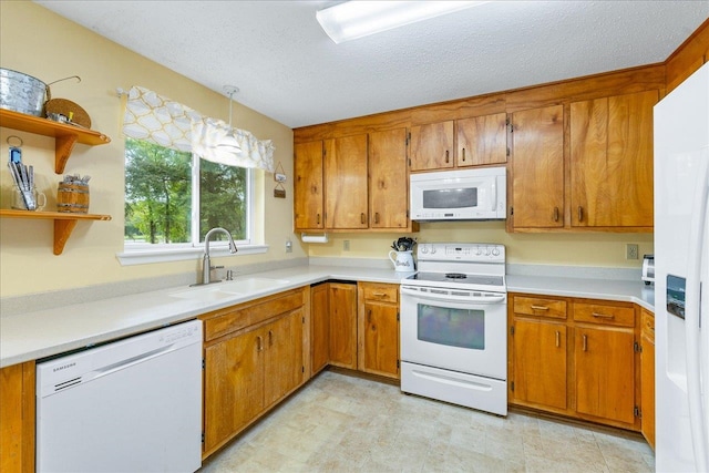 kitchen featuring pendant lighting, a textured ceiling, sink, and white appliances