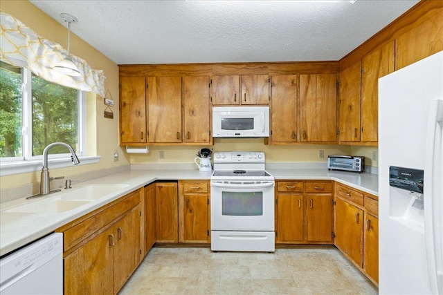 kitchen featuring a textured ceiling, white appliances, sink, and hanging light fixtures