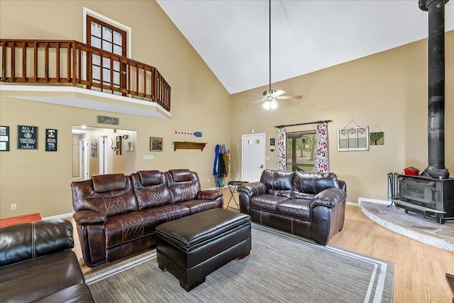living room with a wood stove, hardwood / wood-style floors, ceiling fan, and high vaulted ceiling