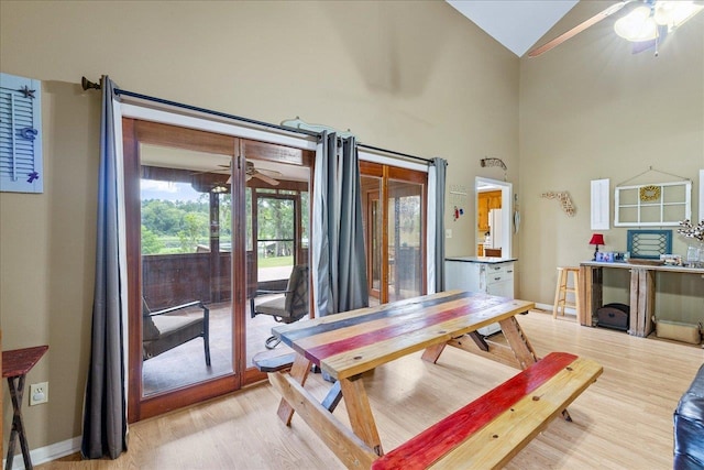 dining room featuring light wood-type flooring, ceiling fan, and high vaulted ceiling