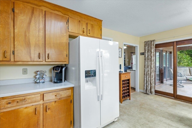kitchen with a textured ceiling and white refrigerator with ice dispenser