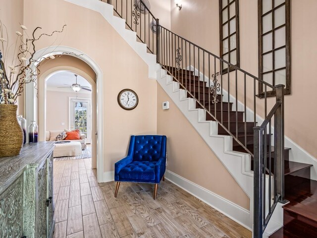 stairway with a high ceiling, wood-type flooring, and ornamental molding