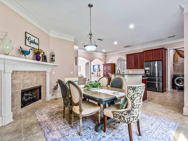 dining room with washer / clothes dryer, a tile fireplace, and crown molding