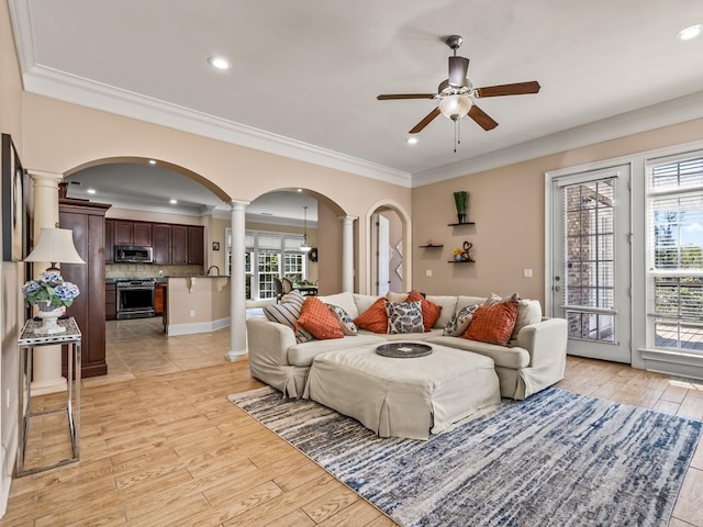 living room featuring ornamental molding, light hardwood / wood-style floors, a healthy amount of sunlight, and ceiling fan