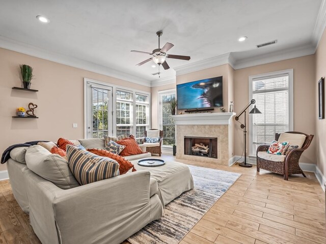 living room featuring a wealth of natural light, a tile fireplace, and light hardwood / wood-style flooring