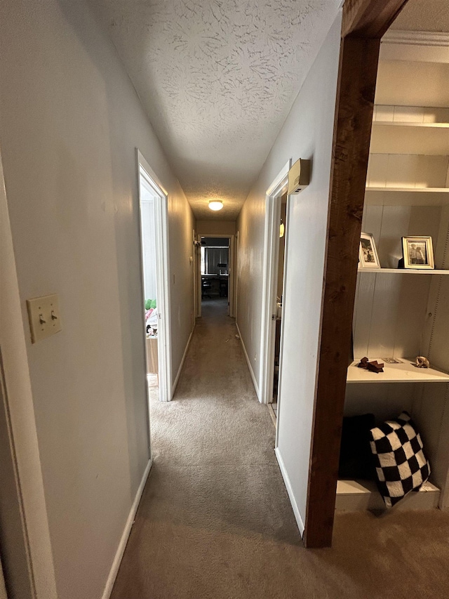 hall featuring carpet flooring and a textured ceiling