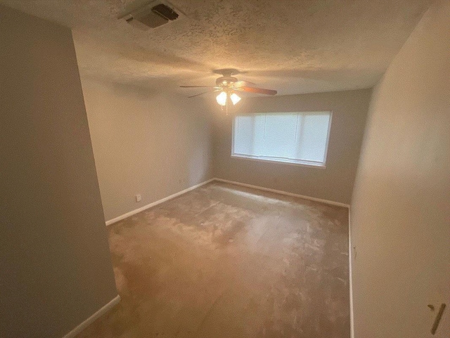 empty room with ceiling fan and a textured ceiling