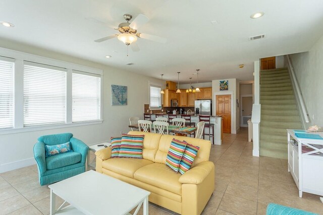 living room featuring ceiling fan with notable chandelier and light tile patterned floors