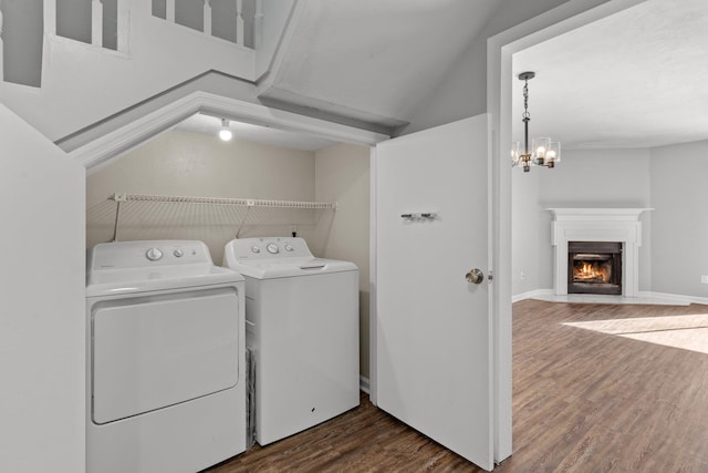 washroom featuring dark hardwood / wood-style flooring, washing machine and clothes dryer, and an inviting chandelier