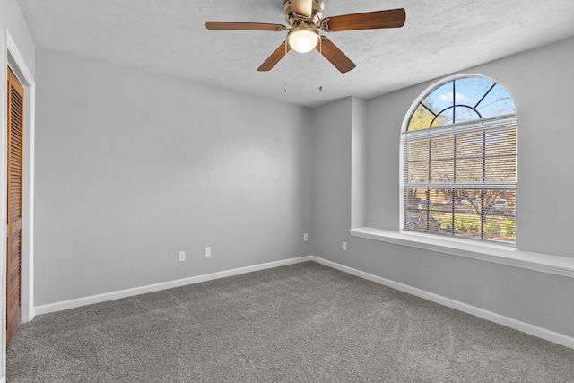 carpeted spare room with a textured ceiling, ceiling fan, and plenty of natural light