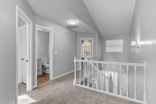 corridor featuring vaulted ceiling and carpet flooring