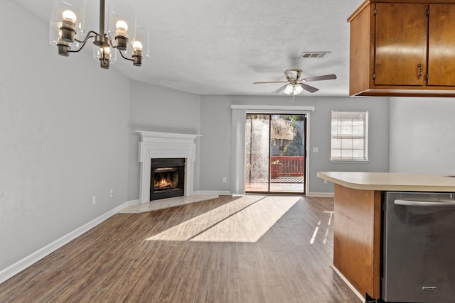 unfurnished living room featuring ceiling fan with notable chandelier and dark hardwood / wood-style floors