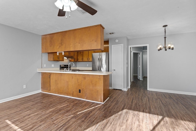 kitchen with kitchen peninsula, stainless steel fridge, dark hardwood / wood-style flooring, sink, and ceiling fan with notable chandelier