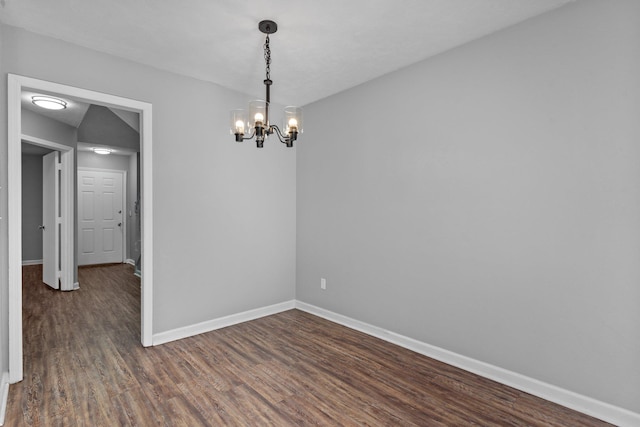 unfurnished room with a notable chandelier and dark hardwood / wood-style flooring